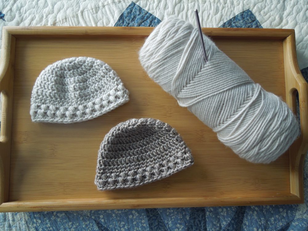 Crochet baby bean hats and yarn on bamboo tray | Marching North
