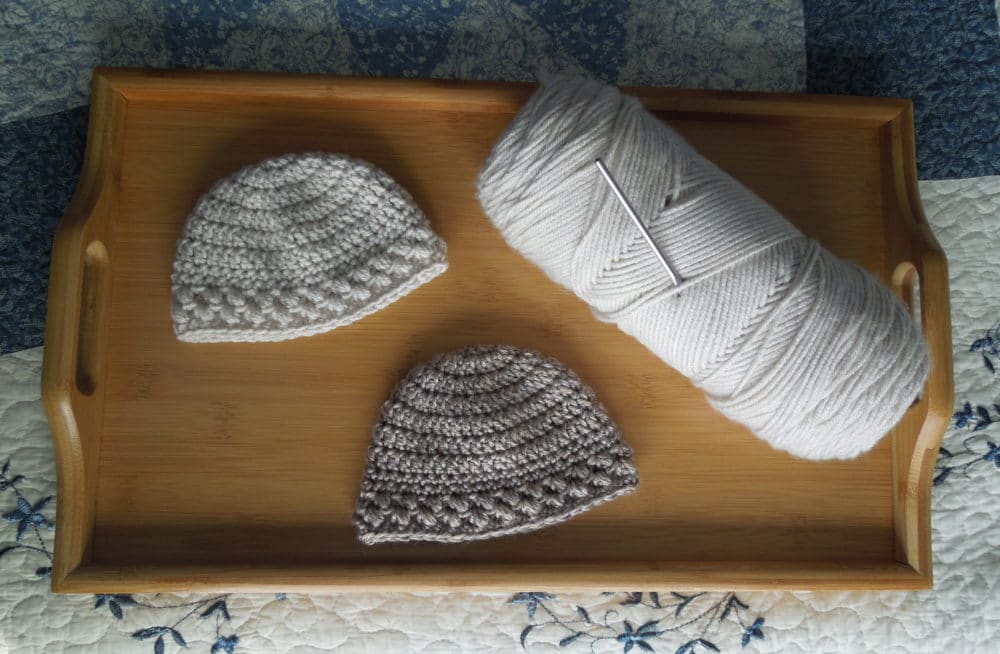 Baby bean hats next to skein of yarn