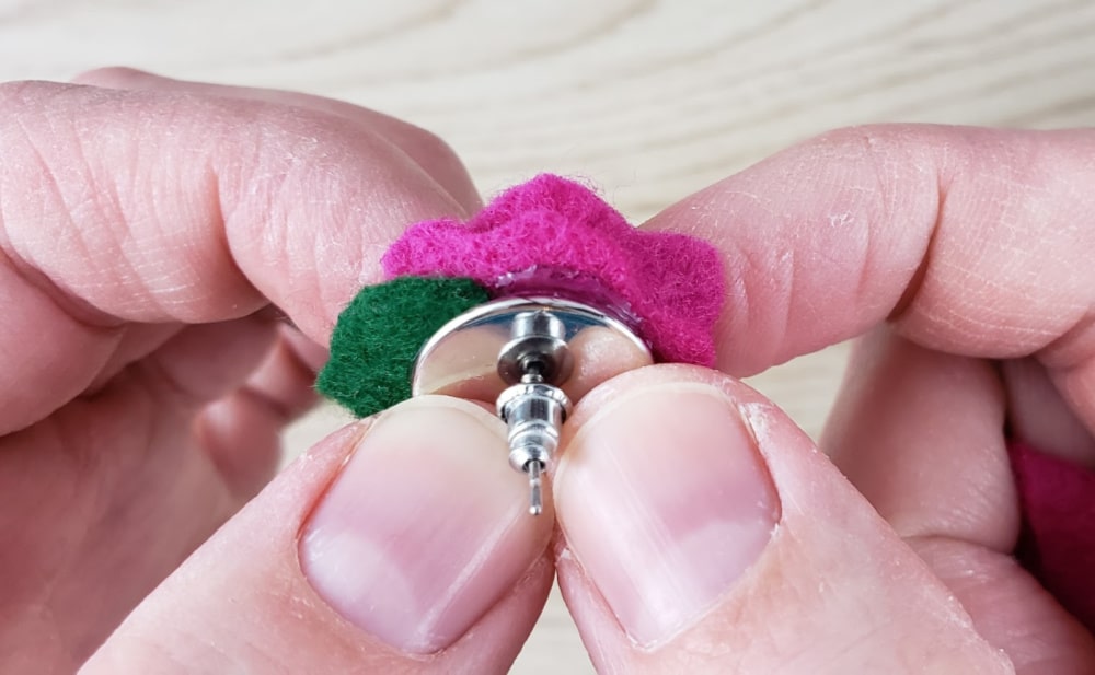 Firmly holding earring bezel onto felt rose while the glue dries