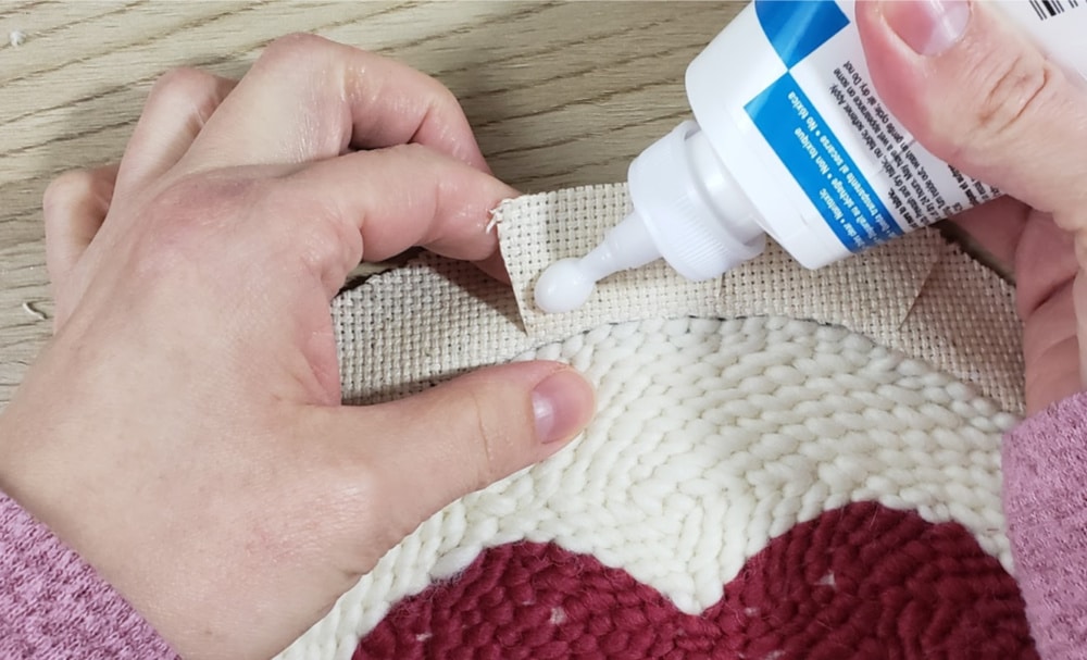 Add glue to the back of the tabs on the punch needle trivet