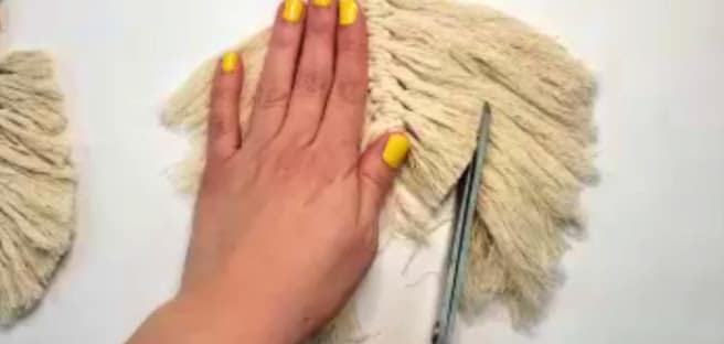 trimming the macrame fringe into a feather shape