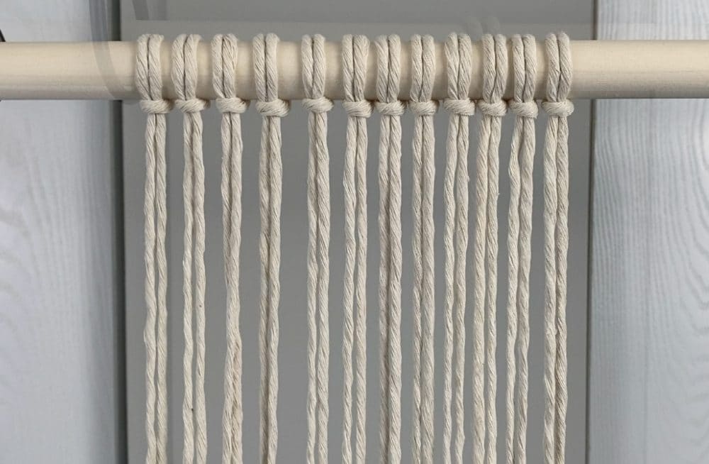 attach the cords to the dowel with larks head knots | hexagon macrame mug coasters