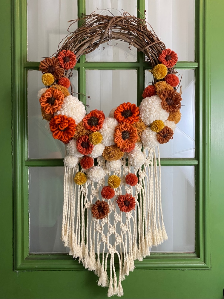 boho fall macrame wreath hung on a green door with a window