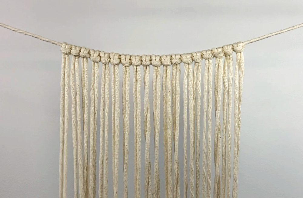 attach the working cords to the holding cord using larks head knots | macrame purse DIY tutorial