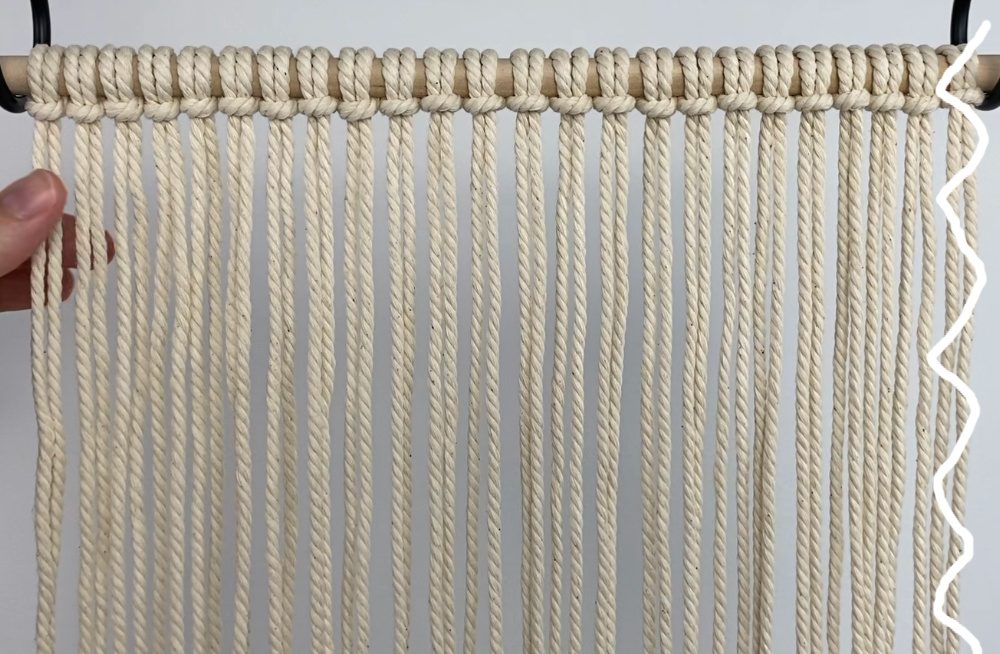 macrame cords attached with larks head knots and hanging from dowel