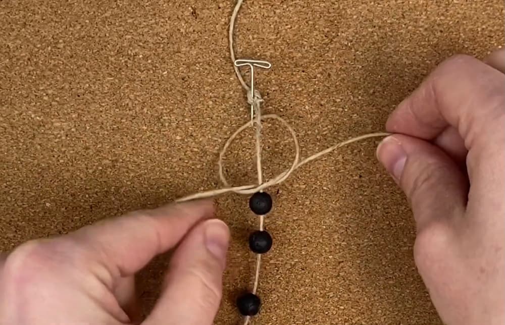 tying a square knot with the working cords of beaded macrame hemp bracelet