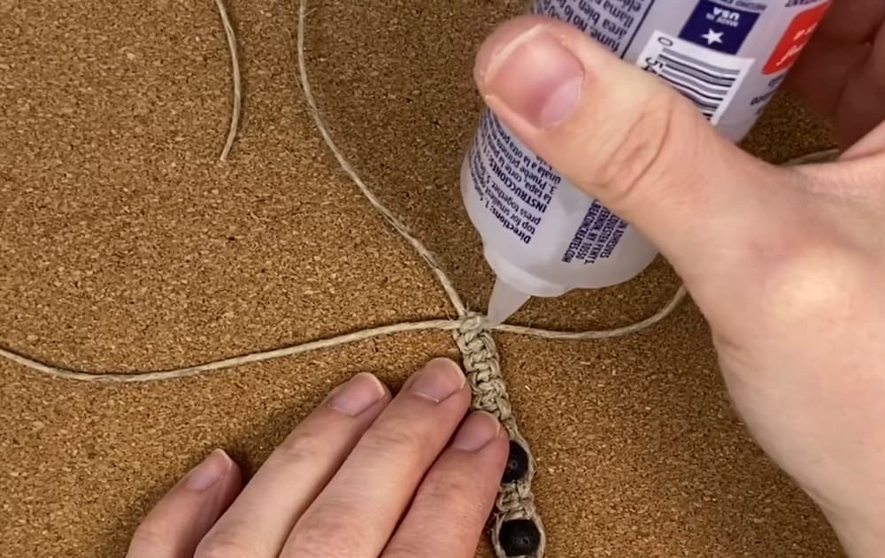 adding glue to the working cord ends of hemp macrame bracelet with beads