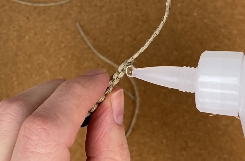 adding a bit more glue to the cut ends of the working cord on this hemp macrame bracelet with beads