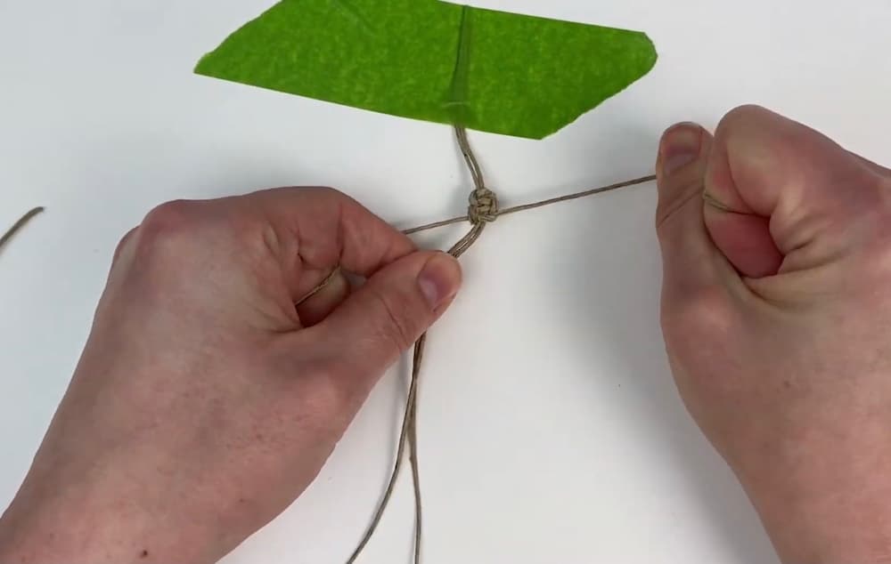 tie the first square knot of the hemp macrame square knot bracelet