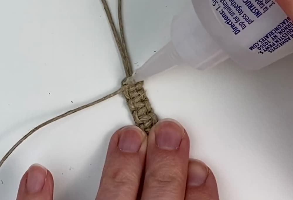 adding glue to the knotted working cords of the square knot bracelet