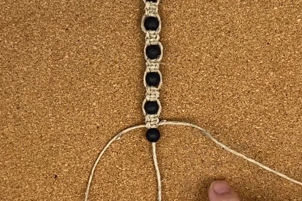 tying square knots in between the beads on macrame hemp bracelet