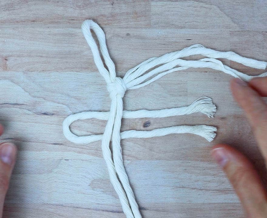 tying the next piece of cord onto the macrame feather 