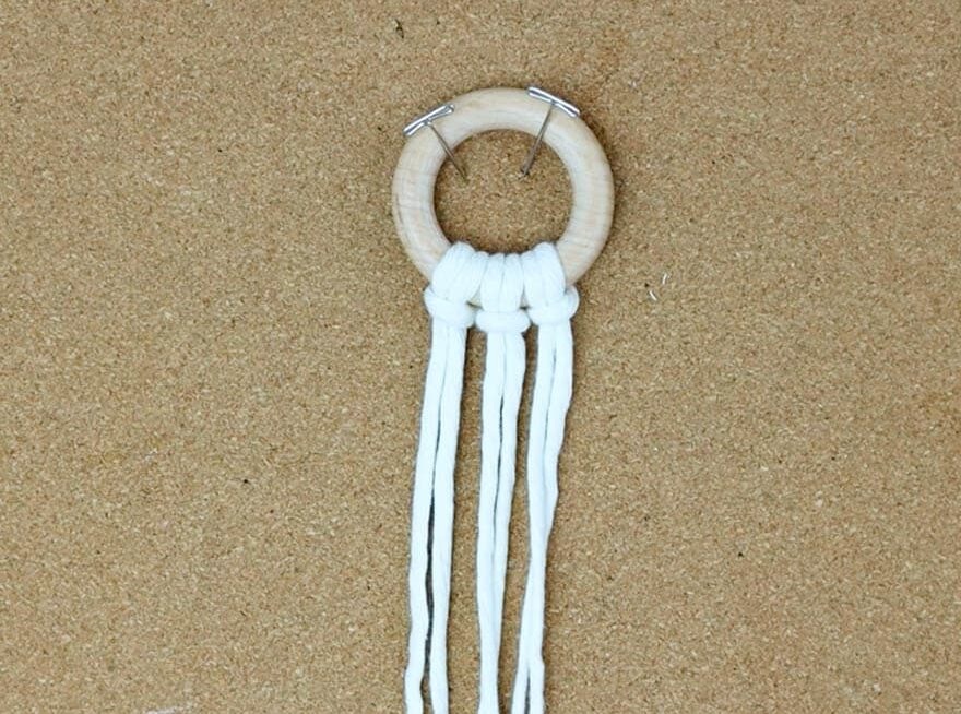 pin the wooden ring down to your cork board with the three pieces of cord attached to it