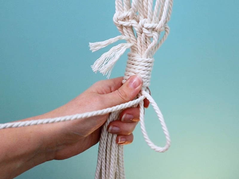 tie a wrapping knot around the cords under the last row of square knots | macrame wall hanging plant hanger