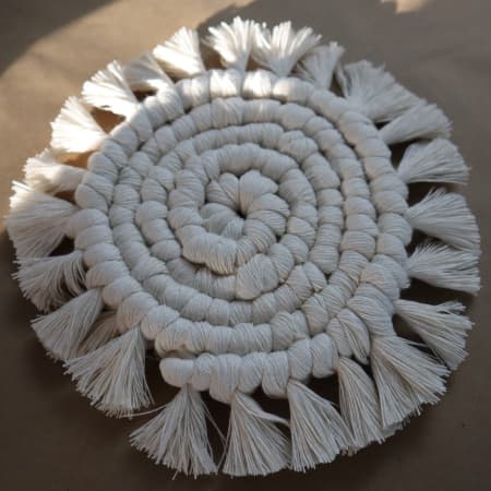 round macrame coaster on a brown desk