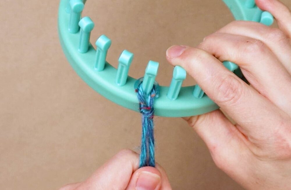 make a slip knot and slide the loop onto the first peg
