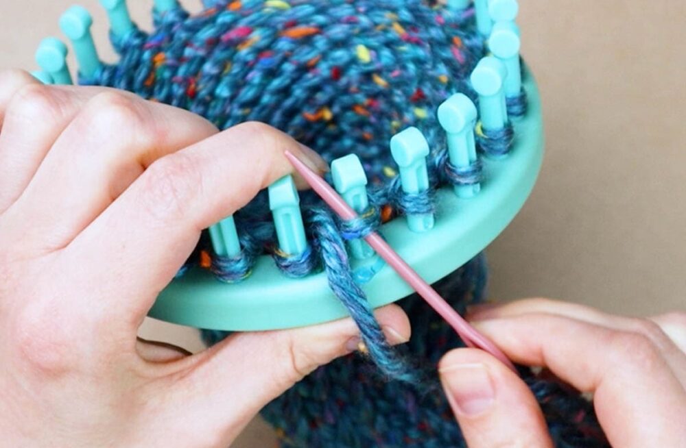 thread the needle under the first peg loop