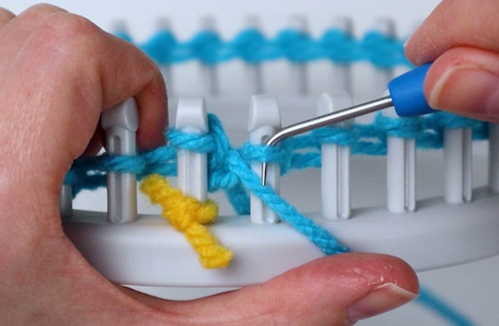 hold the yarn in front and down under the loop on the peg