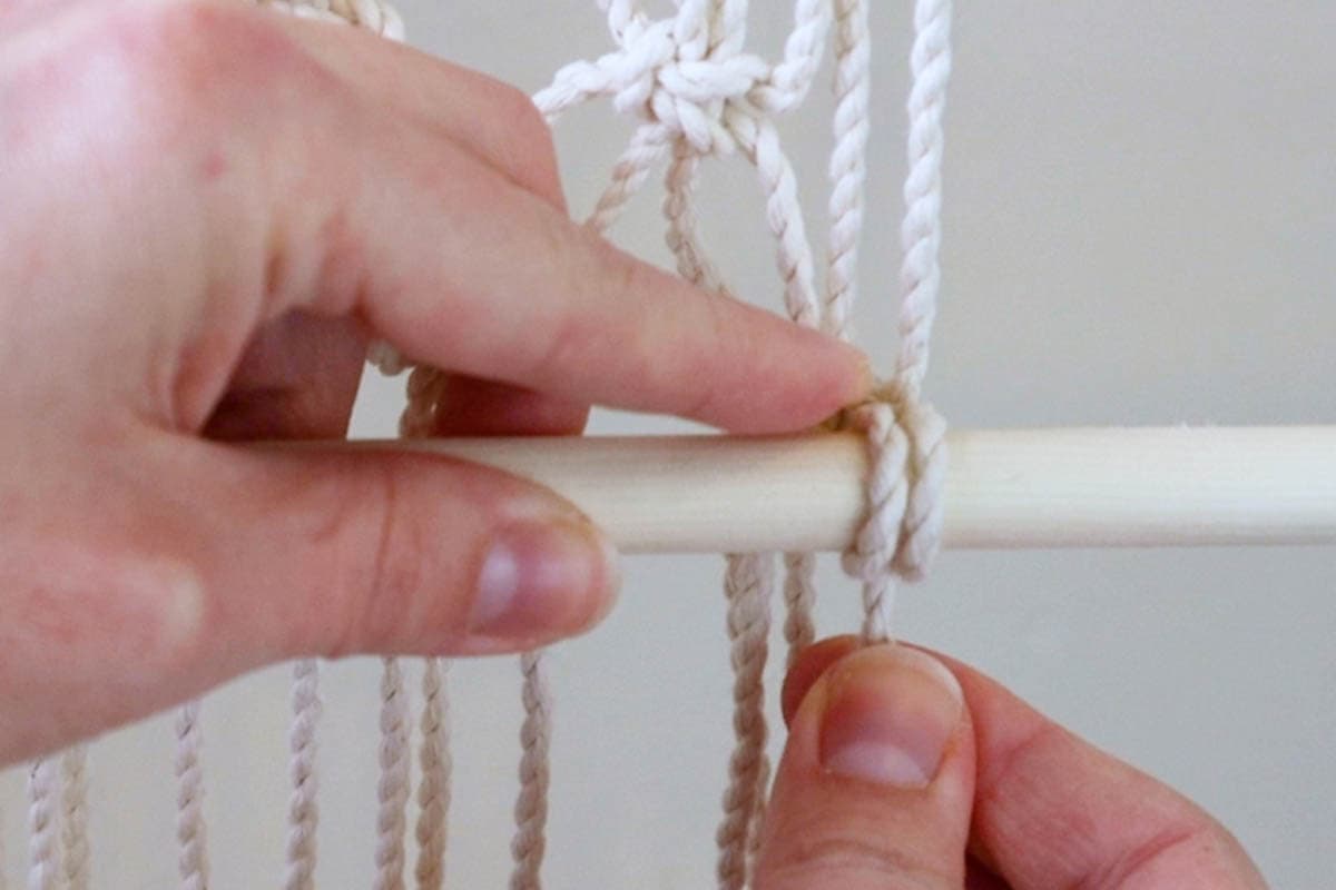 tying one double half hitch knot on the far right to hold the dowel in place