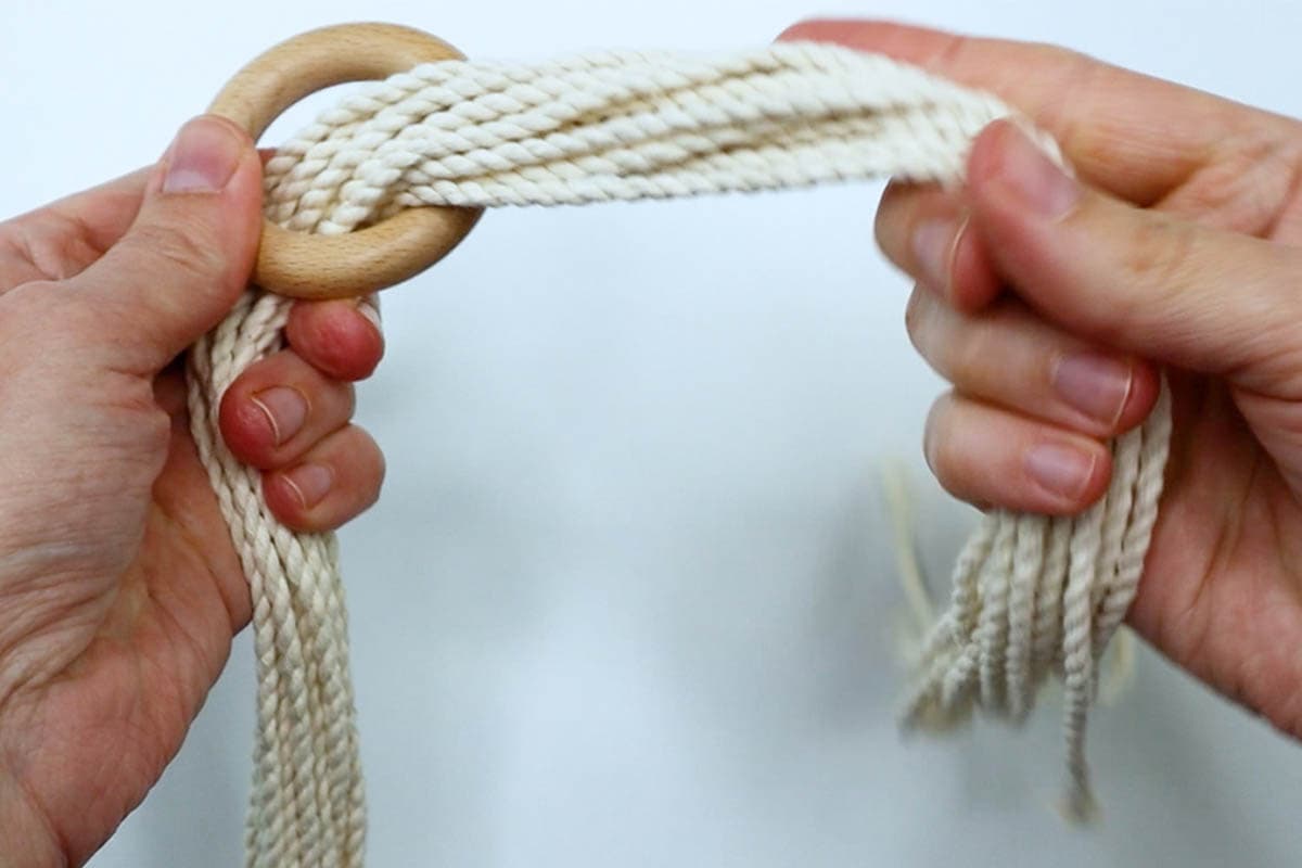 thread the cord ends through the wooden ring