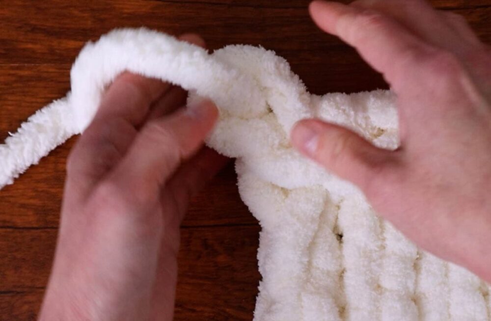 pulling the last yarn tail through the last loop