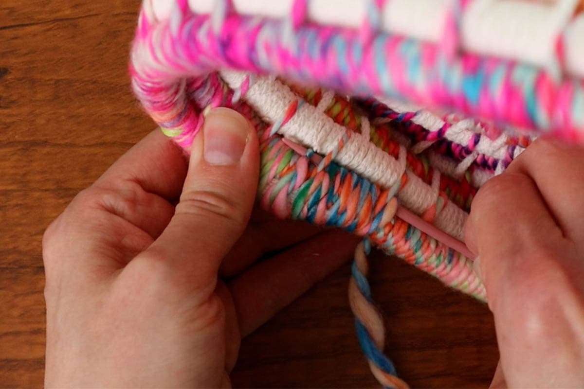 threading the yarn needle back through the last wraps to weave in the yarn tail